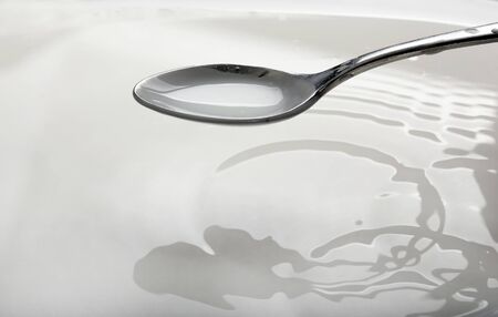spoon full of milk over a bowlの写真素材