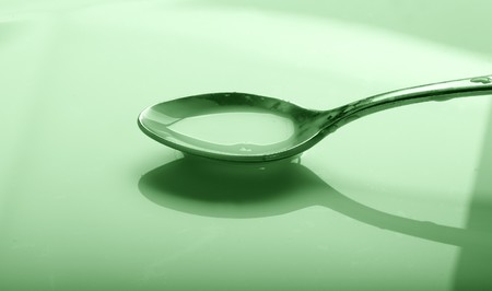 a spoon full of syrup over a bowlの写真素材