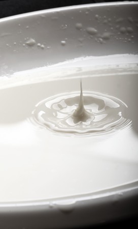 drop of milk falling into a bowlの写真素材