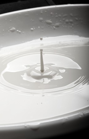 drop of milk falling into a bowlの写真素材