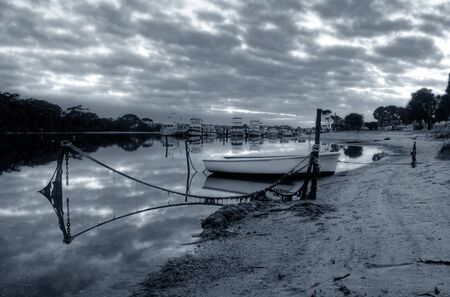 boat resting inside the harbor at low tideの写真素材