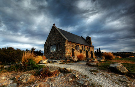 quiet church by a glacier lake against a mountain backdropの写真素材