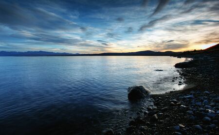 calm waters of a glacier lake with mountains behind の写真素材