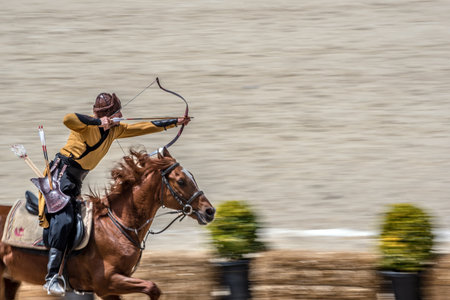 Unidentified medieval archer in costumes of ancient Turkish troops and Ottoman Empire soldiers is aiming with arrow and curve at a target on a horse. ISTANBUL,TURKEY,May 13,2017のeditorial素材