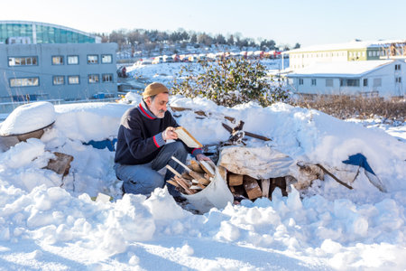 Unidentified old Turkish man puts chopped firewoods in a plastic bucket on a snow day.Istanbul,Turkey.01,January ,2016のeditorial素材