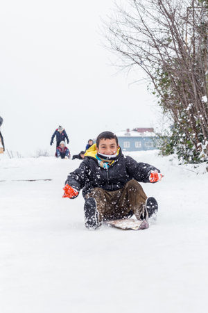 Children slide on snow in old school style with hardwood sled in Istanbul.Happiness and joy...