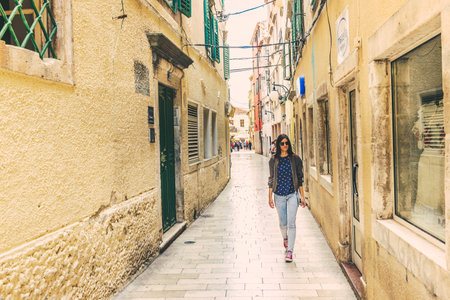 Unidentified girl walking at Street of Sibenik,a popular travel destination for historical architecture,narrow stone streets in Croatia.May 26,2017のeditorial素材