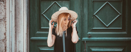 Young attractive woman in fashionable black dress,and stylish round sunglasses and yellow hat poses...