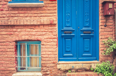 Facade view of vintage style old red brick wall house with blue door and turquoise window. Vintage building and old aged design in Balat.ISTANBUL,TURKEY - May 6,2017のeditorial素材