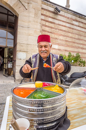 Unidentified man sells Ottoman Macun(Paste),soft, sweet and colorful Turkish toffee paste with Selimiye Mosque foreground.Edirne,Turkey.17 October 2015のeditorial素材