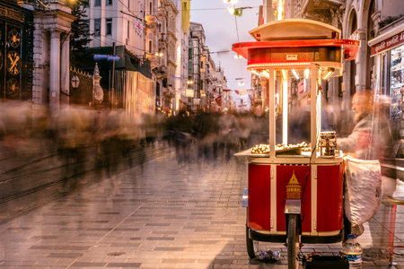 Long exposure or slow shutter speed and blurred image:Unidentified man sells grilled chestnut at Istiklal street,popular destination in Istanbul,Turkey.29 April 2018のeditorial素材