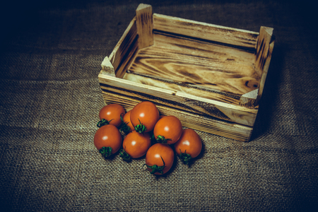 Fresh tomatoes and old burnt wooden crate or box with sackcloth background.Vintage and retro effect added.の写真素材