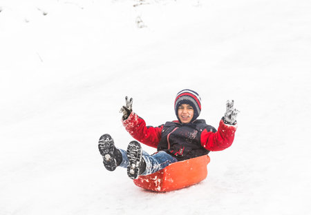 Children slide on snow in old school style with plastic box in Istanbul.Happiness and joy concept.Istanbul,Turkey.31 December,2015のeditorial素材