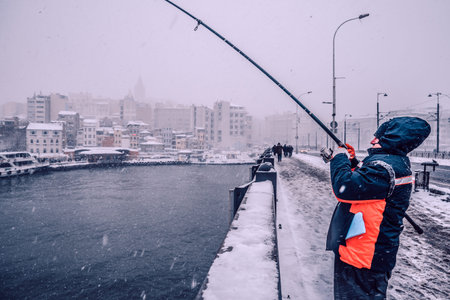 Unidentified people fishing on the galata bridge on a snowy day in winter.Istanbul,Turkey,07 January 2017のeditorial素材