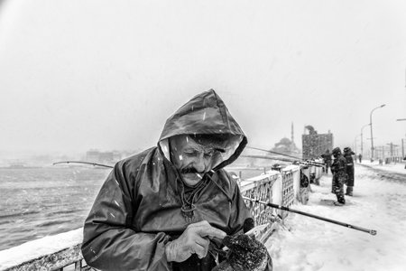 TURKEY, ISTANBUL, JANUARY 07, 2017: Unidentified men fishing at the galata bridge on the heaviest snowfall in Istanbul,Turkeyのeditorial素材