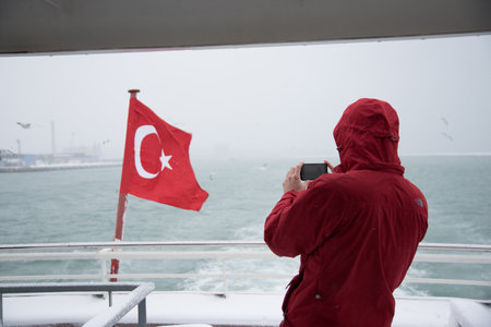 TURKEY, ISTANBUL, JANUARY 07, 2017: Unidentified man taking photos on eminonu ferry on the heaviest snowfall in Istanbul,Turkeyのeditorial素材