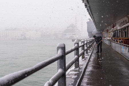 URKEY, ISTANBUL, JANUARY 07, 2017: Unidentified man cleaning at the galata bridge on the heaviest snowfall in Istanbul,Turkeyのeditorial素材