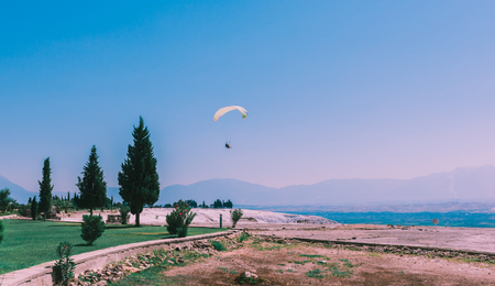 Turquoise color view of Pamukkale (Cotton Castle) is popular with Travertine pools and terraces  and a paraglide on the air.の写真素材