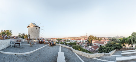 High Resolution panoramic view of Windmills where People eat and drink at a cafe near on a sunny day in Alacati town, a popular destination for traveling and holiday in Izmir,Turkey.26 August 2017.のeditorial素材