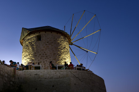 People eating and drinking at a cafe near windmill in the evening in Alacati town, a popular destination for traveling and holiday in Izmir,Turkey.26 August 2017.のeditorial素材