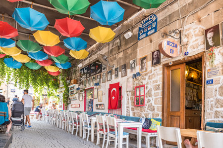 Unidentified People walk at a street with cafe and restaurant with tables and chairs  around at Alacati Town,a popular destination for traveling and vacation in Izmir,Turkey.26 August 2017.のeditorial素材
