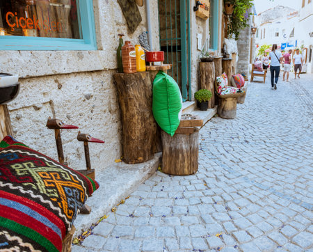 Unidentified People walk at a street with cafe and restaurant with tables and chairs  around at Alacati Town,a popular destination for traveling and vacation in Izmir,Turkey.26 August 2017.のeditorial素材