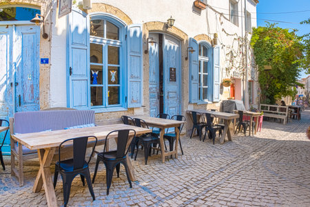 HDR Image-View of cafe and restaurant with tables and chairs at Alacati narrow stone Streets,a popular destination for traveling and vacation in Izmir,Turkey.26 August 2017.のeditorial素材