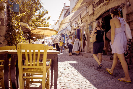 Unidentified People walk at a street with cafe and restaurant with tables and chairs  around at...
