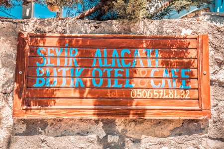 Front view of wooden signage on a white stone wall with plants around it in Izmir,Turkey.26 August 2017.There is a copy space for editing.のeditorial素材