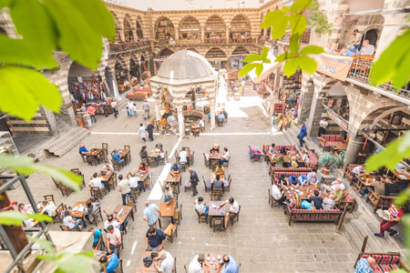 Unidentified people have breakfast and sit courtyard of Hasan Pasha Khan,a medieval inn used for cafes and small shops now in Diyarbakir,Turkey.16 July 2018のeditorial素材
