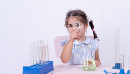 Serious cute little girl in school uniform holds a bulb and looks inside.Selective focus and and concept imageの写真素材