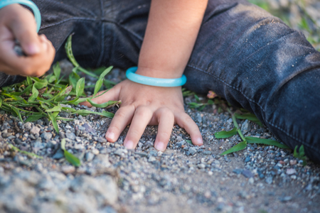 Close view of little girl hands while playing on ground with soul or small stones.の写真素材