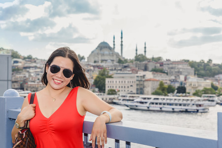 Beautiful Chinese woman poses over Galata Bridge with view of Suleymaniye mosque on background.の写真素材