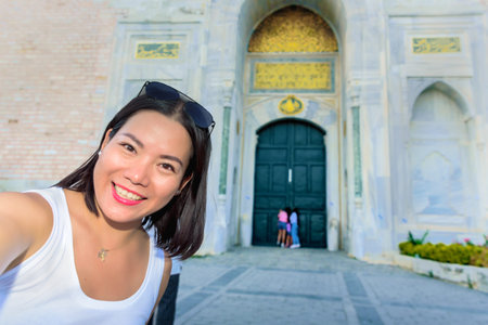 Beautiful woman takes selfie with view of Topkapi Palace on background in Istanbul,Turkeyの写真素材