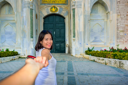 Beautiful woman poses with view of Topkapi Palace on background in Istanbul,Turkey.Follow me conceptの写真素材