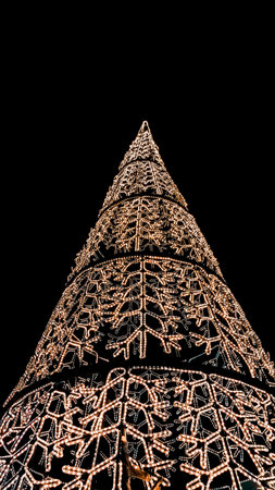 Figures of decorated Christmas tree with light bulbs with dark night background