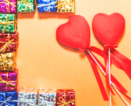 Top view of couple decorative red hearts shapes and small gift boxes on orange background.Holiday concept with isolated background.の写真素材