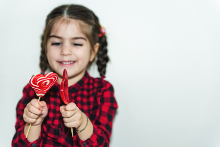 Adorable lovely little girl holds lollipop in heart shaped red candy.Holiday concept with isolated background.の写真素材
