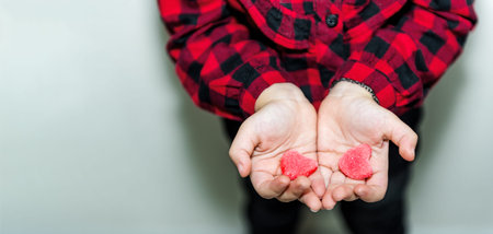 Adorable lovely little girl holds heart shaped red candy in hand.Holiday concept with isolated...