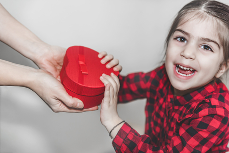 Daughter gives gift box to mum, top view. Holidays, present, childhood concept. Close up of child and mother hands with gift box.Mothers day, Women day conceptの写真素材