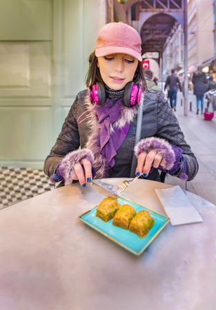 Beautiful woman traveler tourist eats Traditional Turkish dessert called Baklava at cafe near Galata Tower in Beyoglu,Istanbul,Turkey.Copy space for text
の写真素材