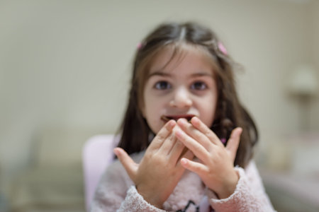 Little cute girl eats surprise chocolate with funny face while looking at camera