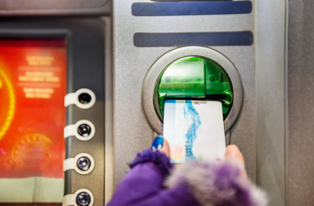 Hands of woman with gloves pulls in debit card at an ATM.ATM cash terminal with display の写真素材
