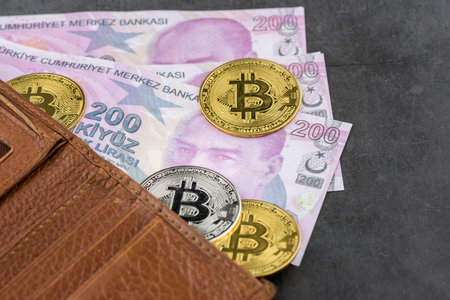 View of metal bitcoins in brown leather wallet and over Turkish Lira banknotes.Concept image for cryptocurrencyの写真素材