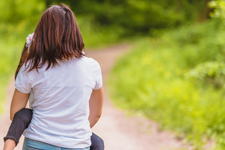 Young mom holds and hugs her little girl in forest.Happy mother and daughter moments with love and natural emotion.Photo of  mother and daughter having good time.の写真素材