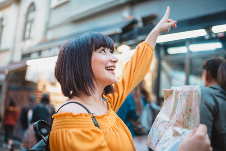 Beautiful young girl in fashionable clothes with map walks around city and looks around.Traveler...