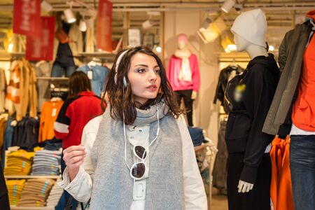 Beautiful young girl in fashionable clothes goes out of a shopping clothes store.の写真素材