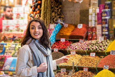 Beautiful woman shows dried herbs or flowers while standing in front of a spice stall sold on stall...