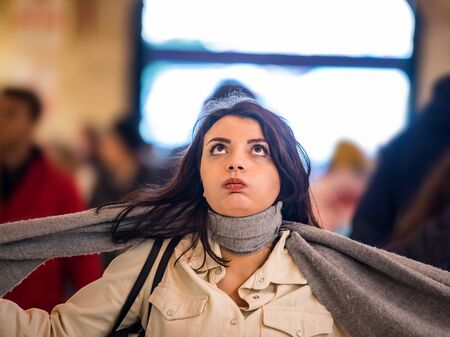 Beautiful woman in fashionable modern clothes suffers social anxiety attack problem while standing crowd of people at road.の写真素材