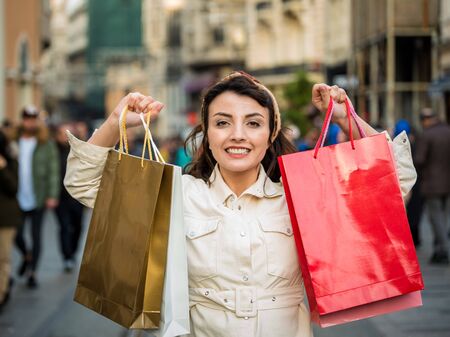 Beautiful attractive young girl in fashionable clothes holds shopping bags after shopping while walking at street. Happy woman with shopping bags.Shopping, lifestyle conceptの写真素材